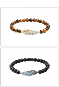 Macro detail of tiger eye and matte black beaded bracelets with crystal wing charms