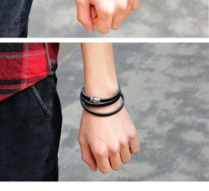 Close-up of a men's multi-layer black leather wrap bracelet with a magnetic silver clasp