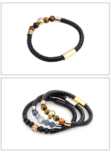 Close-up of leather bracelets with tiger eye beads and gold skull charms for men