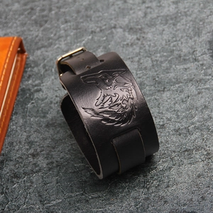 Detailed close-up of a black leather punk wristband featuring an embossed wolf head pattern