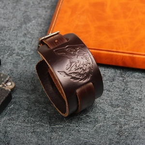 Close-up of embossed wolf head design on wide dark brown leather punk rock bracelet