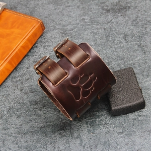 Detail of vintage brown leather wristband featuring embossed paw print and metal buckles