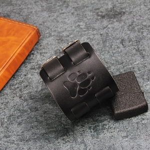 Detail view of black vintage leather wristband featuring a debossed bear paw print design