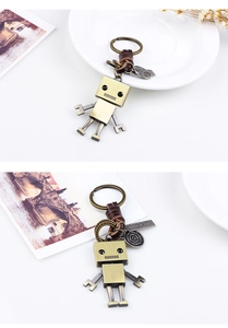 Détail d'un porte-clés robot vintage avec finition bronze et lanière en cuir marron