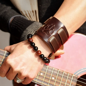Close-up of vintage leather bear paw wristband and stone beads on a guitar player
