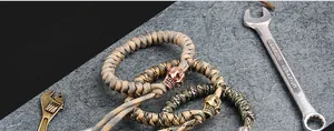Detailed shot of khaki paracord bracelet with skull charm on a grey industrial stone background
