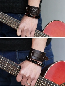 Détail d'une manchette en cuir marron avec gaufrage Om et bracelet en perles sur une guitare