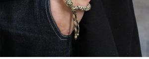 Detail of army green paracord bracelet with a brass skull bead on male wrist