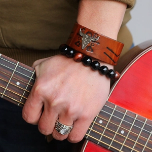 Brown leather bull head bracelet with beaded stone bracelets set against a red guitar