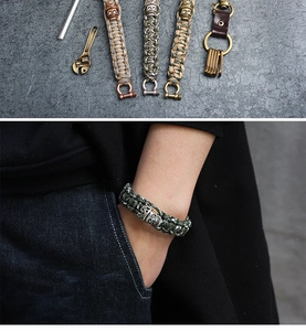 Detailed macro view of woven paracord survival bracelet with a carved metal skull charm