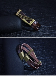 Macro view of vintage bronze feather charm on double-layer brown leather bracelet