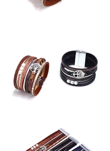 Detail of multi-layer leather bracelet with tree of life charm and magnetic clasp