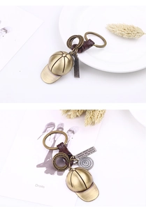 Close-up of bronze baseball cap keychain with braided leather and engraved metal tag