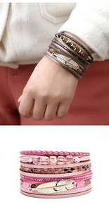 Detail of multi-layer boho leather bracelet with metallic feather and rhinestone accents