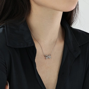 Close-up of S925 sterling silver bow pendant necklace with sparkling cubic zirconia on model