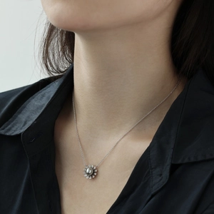 Close-up of S925 silver necklace with sunflower pendant and grey pearl on model