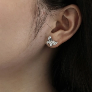 Macro shot of silver butterfly earrings with sparkling cubic zirconia on a model