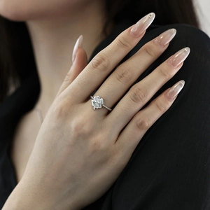 Detail of silver clover ring with green gemstone and rope band on model's hand
