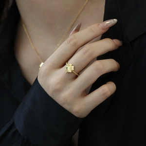 Detailed view of a gold clover ring with green gemstone and spiral twisted band design