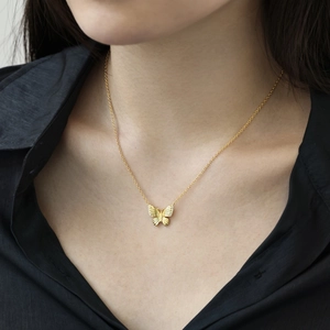 Close-up of a gold butterfly necklace with micro-pave cubic zirconia on a model