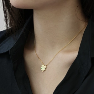 Detailed view of a gold four-leaf clover pendant necklace worn with an elegant black shirt