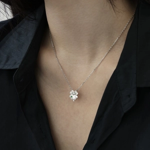 Close-up of S925 silver four-leaf clover necklace with hammered texture and green gem
