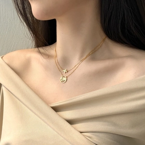 Detail of gold layered necklace with airplane and hollow world map pendants on model
