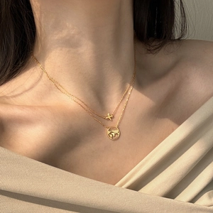 Detailed view of gold layered necklace with airplane and hollow world map pendants