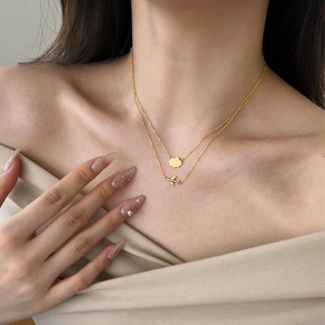 Detailed close-up of double-layer gold necklace featuring cloud and airplane pendants