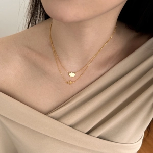 Close-up of gold layered necklace featuring cloud and airplane pendants on a model