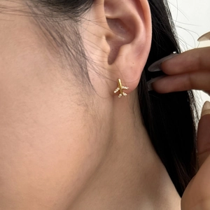 Elegant gold airplane stud earrings with zircons shown on ear for minimalist style