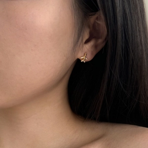 Close-up of golden airplane stud earrings with zircons worn on earlobe for styling