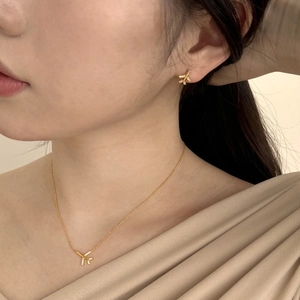 Detail showing elegant gold airplane necklace and earrings set with cubic zirconia