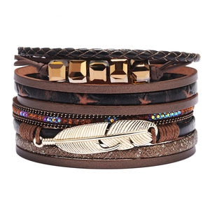 Pulsera multicapa de cuero con dije de pluma dorada y detalles de cristales brillantes