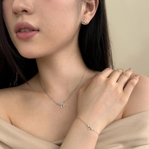 Macro shot of silver airplane jewelry set with sparkling zircons worn by a model