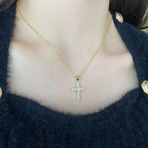 Elegant gold cross necklace with sparkling zircon pendant on model with black sweater