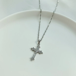 Detailed view of S925 silver cross pendant necklace with sparkling zircon on a ceramic dish