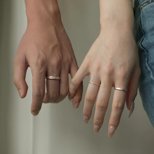 Close-up of rose gold couple rings with diamonds worn on hands for a romantic look
