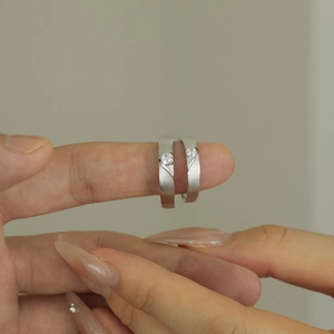 Close-up of S925 silver couple rings featuring a brushed finish and small inlaid diamonds