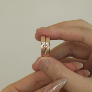 Macro detail of rose gold couple rings featuring brushed finish and heart-shaped groove