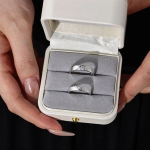 Macro detail of brushed silver couple rings with round zircon in a premium jewelry box