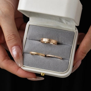 Detailed view of three rose gold rings with engraved patterns and pavé crystals in a box