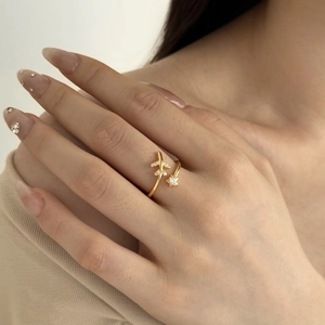 Detail van verstelbare gouden ring met sprankelende vliegtuig- en sterbedeltjes