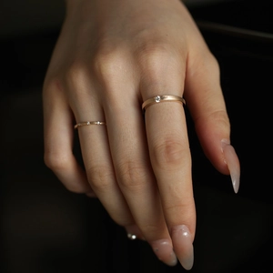 Close-up of matte gold ring with diamond and slim pavé eternity band on hand