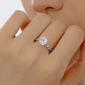 Macro shot of 2 carat round moissanite ring with twisted pavé band on a female finger