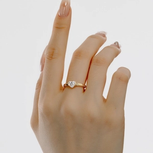 Close-up of a heart-cut cubic zirconia ring on a model hand with a golden finish