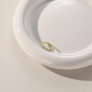 Gros plan sur une bague torsadée dorée avec poinçon S925 et pavé de zircons fins