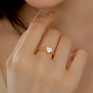 Macro shot of a heart-cut cubic zirconia ring in a gold-plated setting worn on a finger