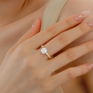 Macro shot of 2ct round cut solitaire gold ring with twisted band on a model hand