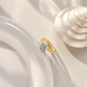 Macro shot of 2-carat round diamond ring with twisted gold band on white ceramic vessel